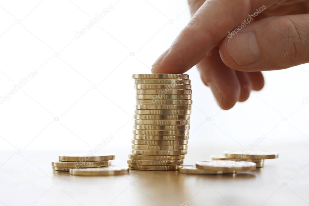 Hand put more gold coins to money stack on white background. Close-up of hand putting a coin to stack of coins. Business finance and money concept