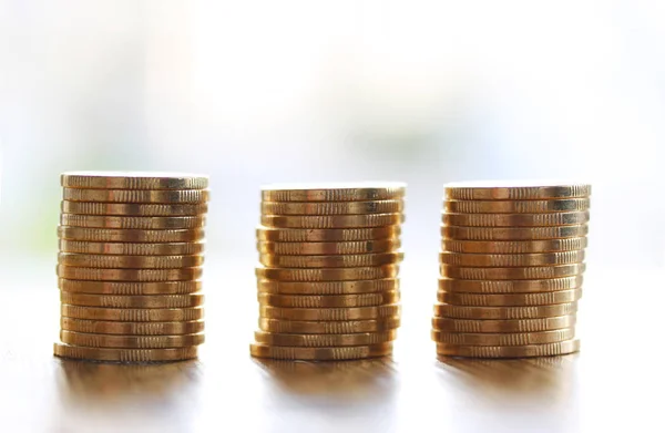 Three stacks of gold money coins coin in pile on blurred background