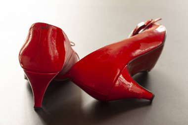 Bir çift kırmızı, parlak, iyileştirici ayakkabı. Ayakkabının biri ayakta duruyor ve diğeri yan tarafta yatıyor. Seçici odaklı arkaplan resmi.