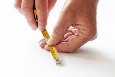 Ölçüm bandıyla çalışan adam. Beyaz arkaplanda el örgüsü bandı tutan ellerin yakın çekimi.