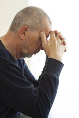 Mutsuz depresif erkek iş, endişe, kalp kırıklığı ve sağlık sigortası konsepti yüzünden stresli bir masada oturuyor. Portreyi kapat.