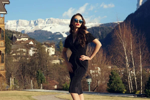 Vonzó nő fekete ruhában pózol ellen hegyek a háttérben — Stock Fotó