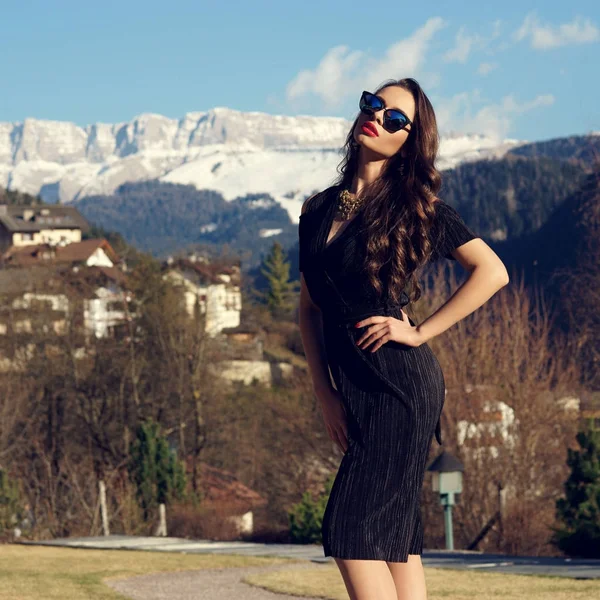 Mujer atractiva en vestido negro posando contra las montañas en el fondo — Foto de Stock