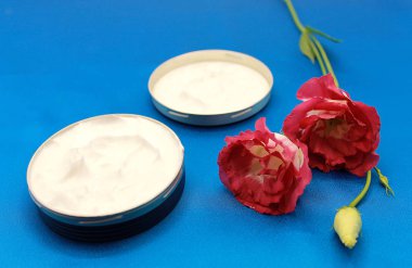 Mavi arka planda doğal yüz kremi ve Japon gülü.