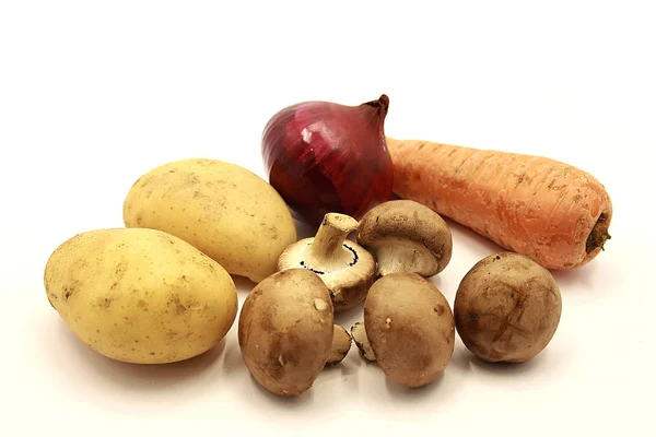 Vegetables: black and purple onions, carrots, potatoes, mushrooms isolated on a white background