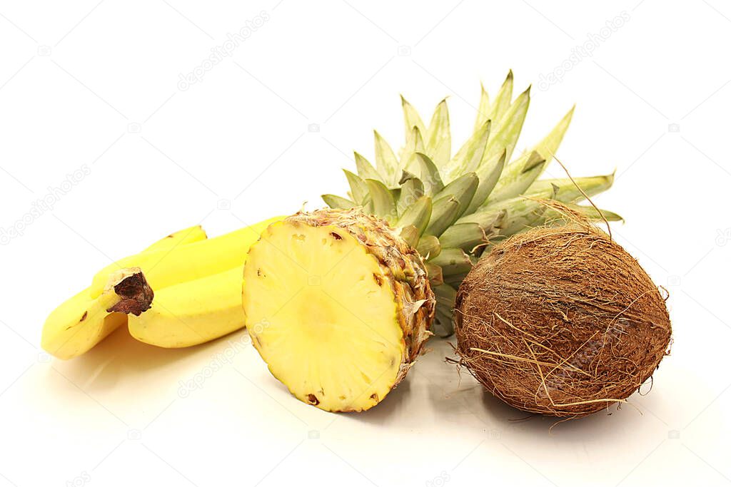 Ripe sliced pineapple, bananas and coconut closeup isolated on a white background