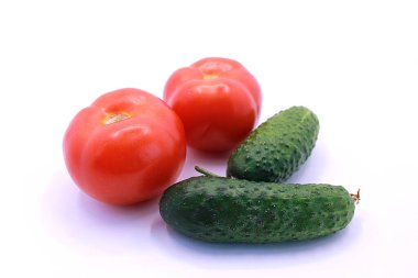 Beyaz arka planda olgun domates ve salatalık fotoğrafı, yakın plan.