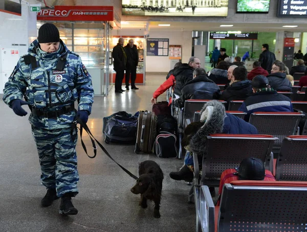 Um policial verifica a sala de espera da estação ferroviária com um cão de serviço . — Fotografia de Stock