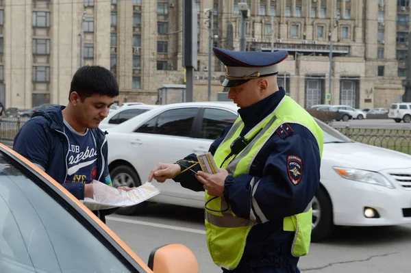 The inspector dorozhno-patrol service of the police checks the documents of a taxi driver in Central Moscow. — Stock Photo, Image