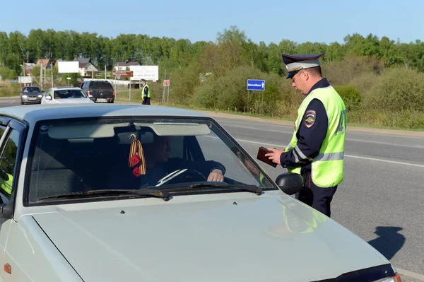 De ambtenaar van de politie controleert de documenten van de bestuurder van de auto. — Stockfoto