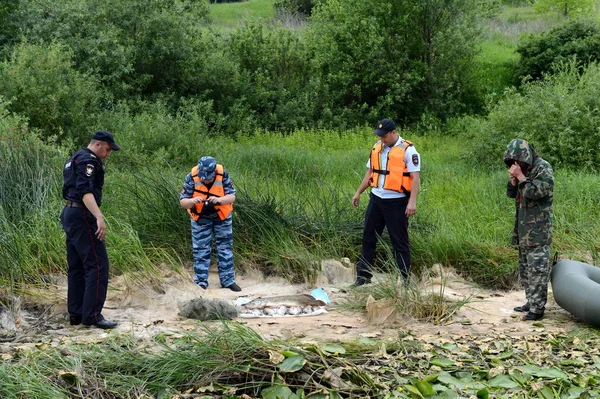 stock image  Police officers take out fish from a fisherman for poaching on the Oka River.