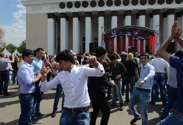  Мигранты танцуют во время празднования Дня Победы в выставочном центре
.