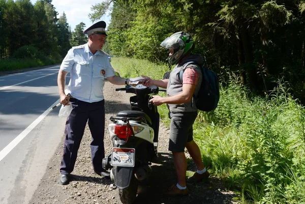 Inspektör av vägen polisen patrullen kontrollerar dokumenten från föraren av motorcykeln. — Stockfoto