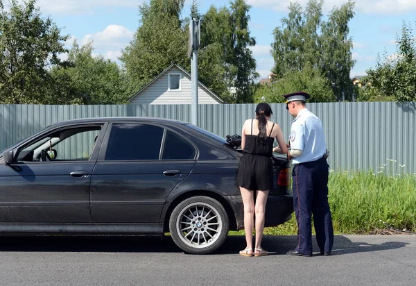 L'inspecteur de la patrouille de police routière vérifie les documents du conducteur de la voiture . — Photo