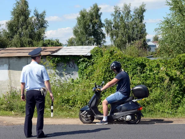 L'inspecteur de la patrouille de police routière a arrêté le conducteur de la moto sur la route . — Photo