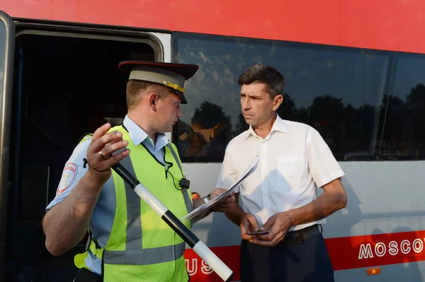 L'inspecteur de la patrouille de police routière vérifie les documents du conducteur de l'autobus interurbain . — Photo