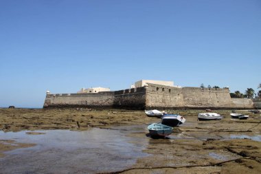 Cadiz, İspanya - 5 Temmuz 2011: Tekneler Cadiz sahil Castillo Fortaleza de Santa Catalina Kalesi yakınında kapalı.