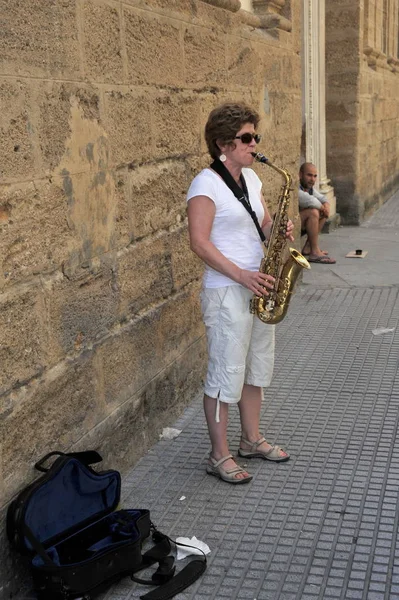 Uma mulher desconhecida toca saxofone na antiga rua da cidade de Cádiz . — Fotografia de Stock