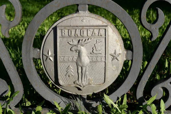 Coat of arms of the city of Vologda on the metal fence of the Railway Station Square. City of Cherepovets. Vologda Region