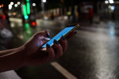 Cep telefonu gece şehrinde kadınların elinde.