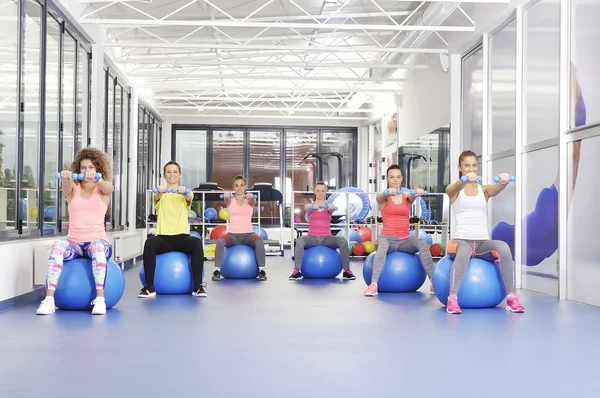 Grupo de hermosas mujeres jóvenes haciendo ejercicio en bolas de pilates azules y sonriendo — Foto de Stock