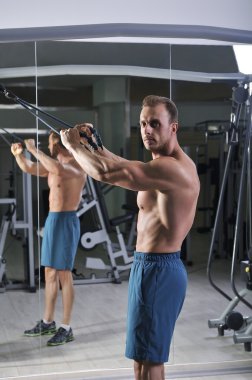 Geri kabloları ile egzersiz yaparak yakışıklı güçlü atletik bir adam. Mükemmel abs, sırt ve göğüs ile güçlü vücut geliştirmeci.