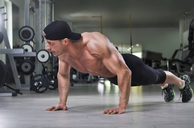 Push up salonunda gerçekleştirme yakışıklı güçlü atletik bir adam. Mükemmel sırt, omuz, pazı, triceps ve göğüs ile güçlü vücut geliştirmeci.