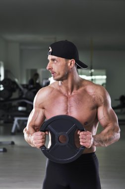 Statik egzersiz kilo ile gerçekleştirme yakışıklı güçlü atletik bir adam. Mükemmel, omuzlar, kollar ve göğüs ile güçlü vücut geliştirmeci.