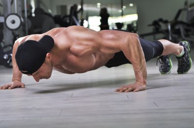 Push up salonunda gerçekleştirme yakışıklı güçlü atletik bir adam. Mükemmel sırt, omuz, pazı, triceps ve göğüs ile güçlü vücut geliştirmeci.