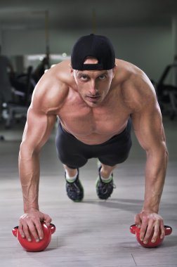 Push up su ısıtıcısı çan ile gerçekleştirme yakışıklı güçlü atletik bir adam. Mükemmel omuzlar, pazı ve triceps güçlü vücut geliştirmeci.