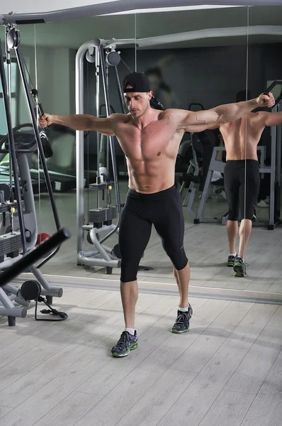 Kablo crossover egzersiz yapan yakışıklı güçlü atletik erkek. Mükemmel abs, göğüs ve kollar ile güçlü vücut geliştirmeci.