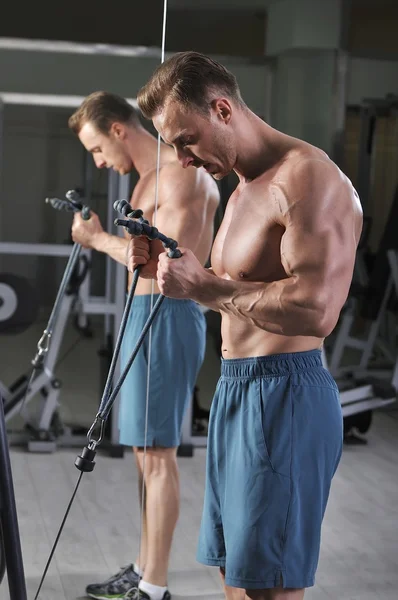 Kabloları ile pazı egzersiz yapan yakışıklı güçlü atletik erkek. Mükemmel kaslı güçlü vücut geliştirmeci.