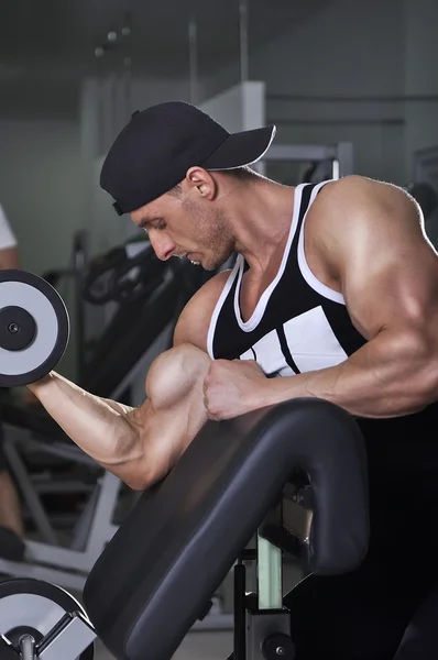 Bonito homem atlético poderoso fazendo exercício bíceps com halteres. Forte fisiculturista com músculos perfeitos . — Fotografia de Stock