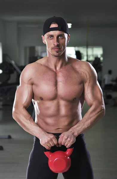 Stilig kraftfulla atletisk man poserar på gymmet med panna ringklocka. Stark bodybuilder med perfekt muskulös abs, armar och bröst. — Stockfoto
