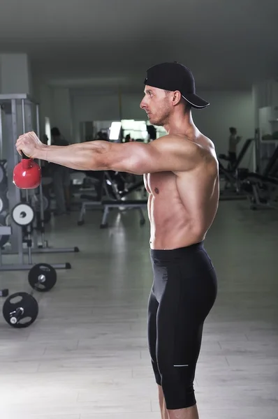 Knappe krachtige atletische man schouder oefening doet met waterkoker bell. Sterke bodybuilder met perfecte gespierde abs, armen en borst. — Stockfoto