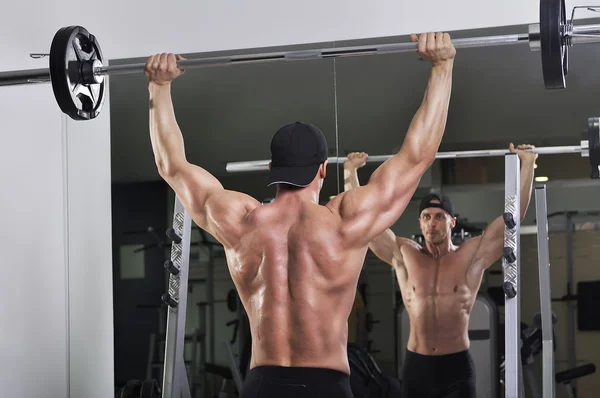 Knappe krachtige atletische man barbell shoulder press oefening doet. Sterke bodybuilder met perfecte spieren. — Stockfoto