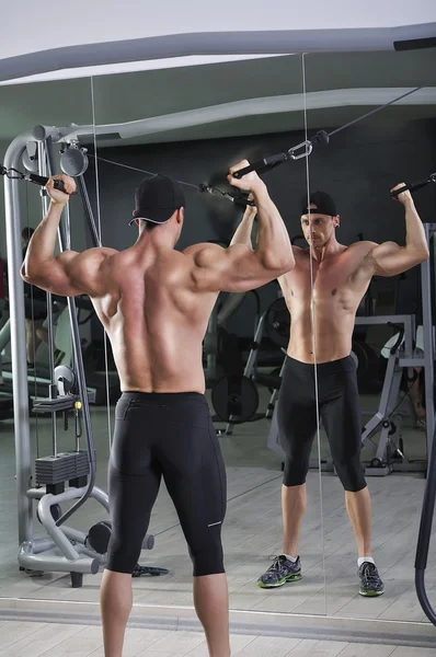 Όμορφος ισχυρό Αθλητικός άνδρας κάνει άσκηση δικέφαλους με καλώδια. Ισχυρή bodybuilder με τέλεια τους μύες. — Φωτογραφία Αρχείου