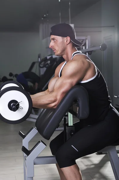 Bonito homem atlético poderoso fazendo exercício bíceps com barra. Forte fisiculturista com músculos perfeitos . — Fotografia de Stock