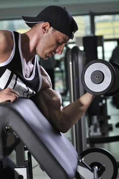 Bonito homem atlético poderoso fazendo exercício bíceps com halteres. Forte fisiculturista com músculos perfeitos . — Fotografia de Stock