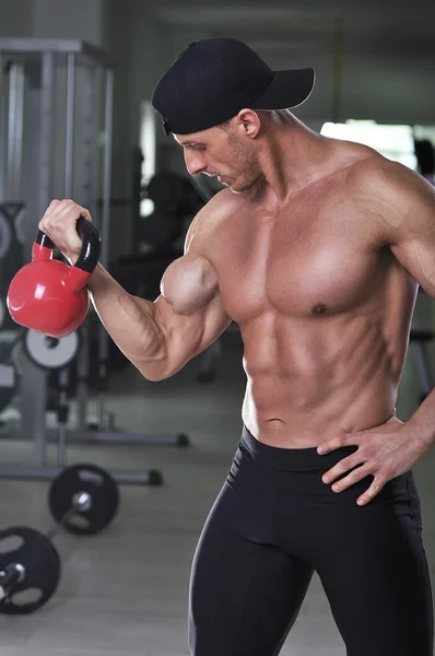 Knappe krachtige atletische man je biceps-oefening doet met waterkoker bell. Sterke bodybuilder met perfecte gespierde abs, armen en borst. — Stockfoto