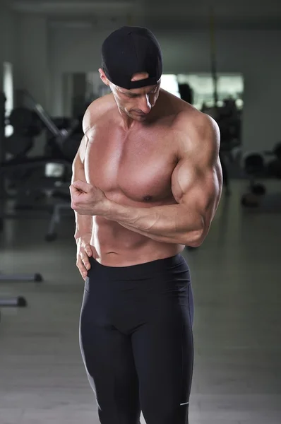 Un hombre atlético atractivo y poderoso posando en el gimnasio. Culturista fuerte con abdominales, hombros, brazos y pecho perfectos . —  Fotos de Stock