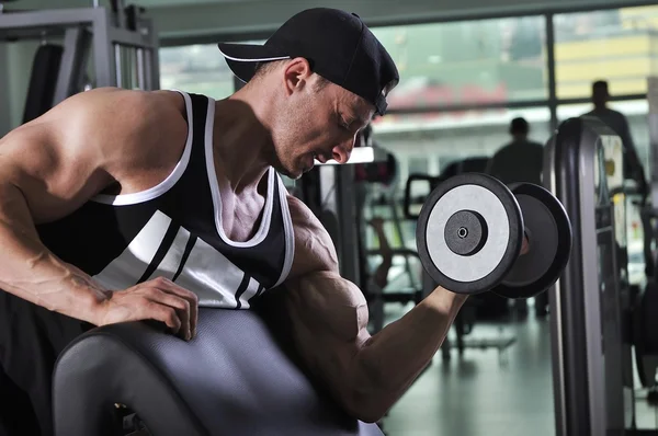 Bonito homem atlético poderoso fazendo exercício bíceps com halteres. Forte fisiculturista com músculos perfeitos . — Fotografia de Stock