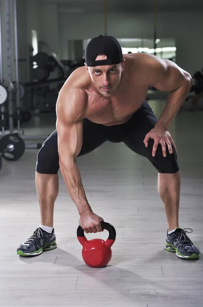 Όμορφος ισχυρό Αθλητικός άνδρας εκτέλεση άσκησης κουδούνι βραστήρα. Ισχυρή bodybuilder με τέλεια ώμους, δικέφαλου και triceps. — Φωτογραφία Αρχείου