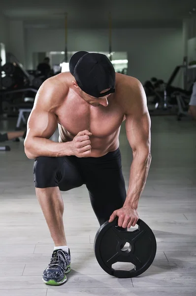 Handsome powerful athletic man preparing for the exercise with weight. Strong bodybuilder with perfect, shoulders, arms and chest. — Stock Photo, Image