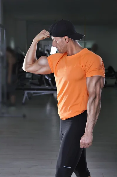 Jóképű sportos férfi pózol az edzőteremben. Erős testépítő a tökéletes izmos karok. — Stock Fotó