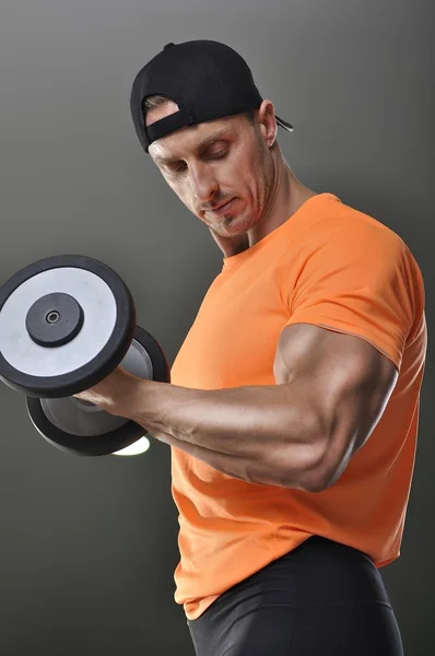 Bonito homem atlético poderoso realizando exercício bíceps com halteres. Forte fisiculturista com bíceps perfeito e tríceps . — Fotografia de Stock