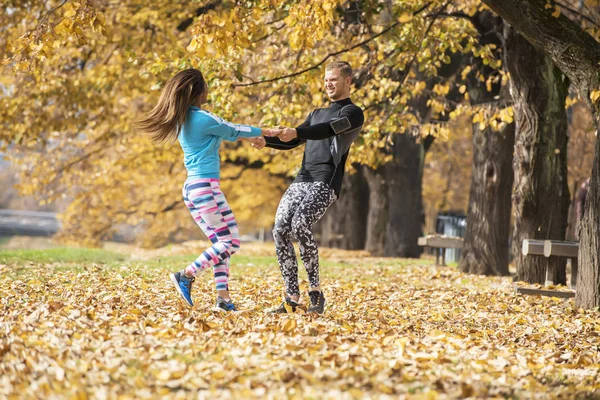 Schöne junge Paar genießen und rotieren zusammen im Park. Herbstliches Umfeld. — Stockfoto
