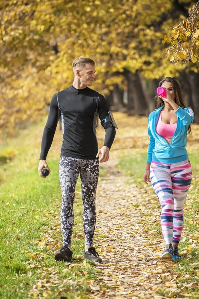 Schönes junges Paar, das sich nach dem Laufen im Park abkühlt. Herbstliches Umfeld. — Stockfoto