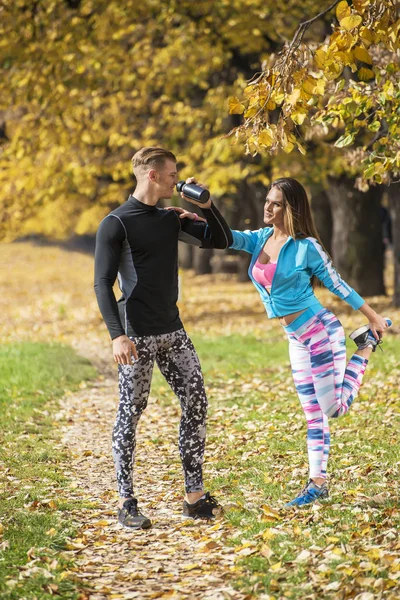 Schönes junges Paar, das sich nach dem Laufen im Park abkühlt. Herbstliches Umfeld. — Stockfoto