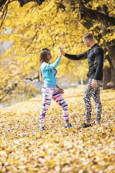 Schönes junges Paar feiert nach erfolgreichem Lauf im Park. Herbstliches Umfeld. — Stockfoto